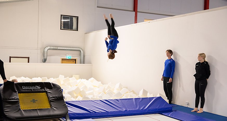 En gymnast övar en volt ner i klossgropen. Två gymnaster tittar på. Foto: Josefin Lundin