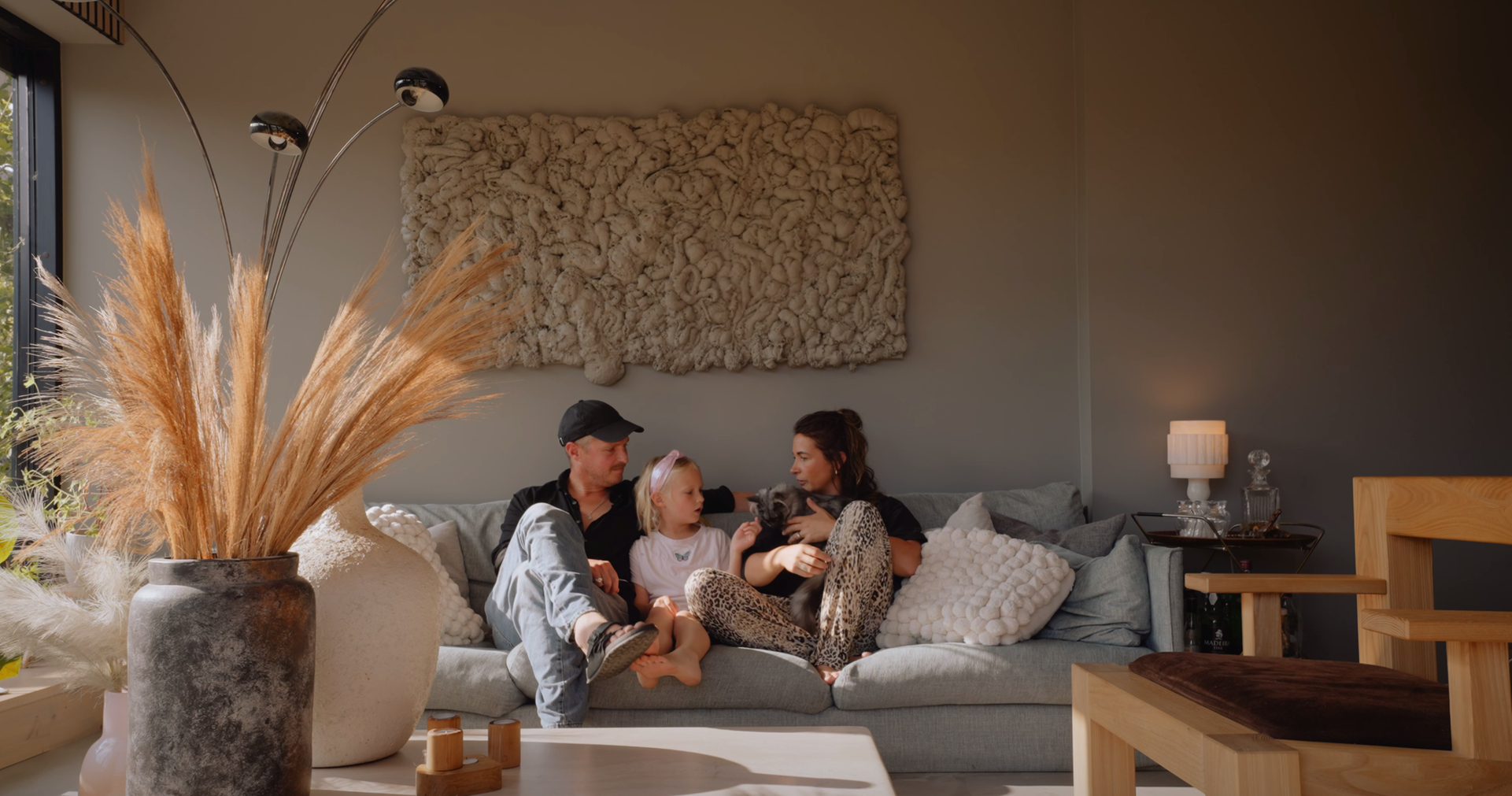 En kvinna och en man sitter i en soffa. Mellan dem sitter ett barn.